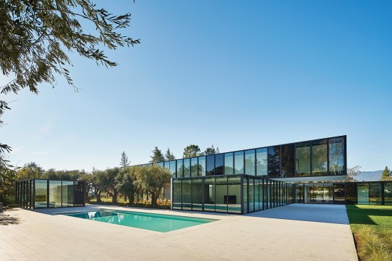The glazed northern façade provides views of the backyard, swimming pool, and freestanding pool house.