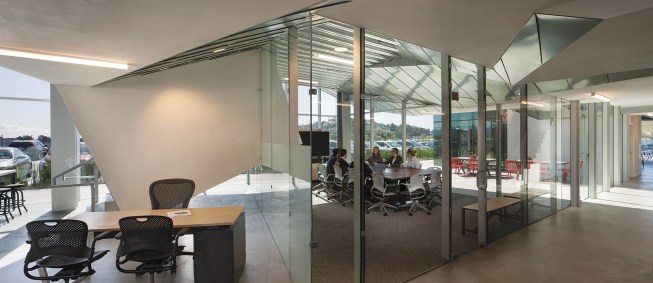 A passageway runs the length of both floors; on the lower level, a glass-walled conference room opens onto the entry plaza.