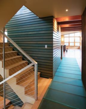 Inside the Johnson house, salvaged fir slats echo the exterior siding, and glass panels on the floor transmit light to a hallway below.