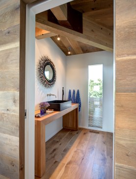 First-floor powder room: The bulk of the simple wood
vanity mirrors the hefty post-and-beam structure of the ceiling.