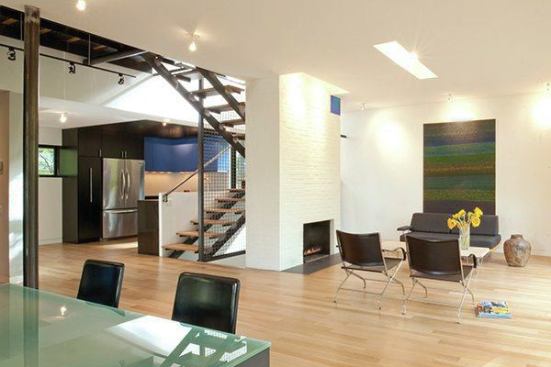 An open plan distinguishes the main level of the house. Pale oak flooring, all-white walls, and few furnishishings make for a bright, spacious interior.