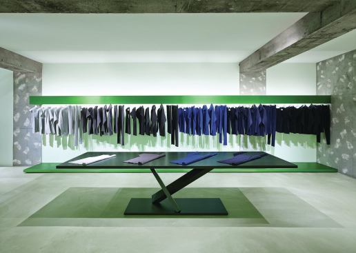 The lower level features green displays. Yoshioka’s office designed the steel tables with the angled legs for Italian furniture maker Desalto. Known as Element, the series complements the sculptural, freestanding steel clothing racks deployed throughout. 