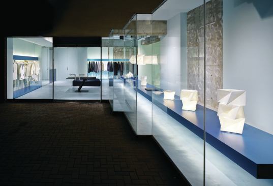 There are two street entrances to the store. Alongside one of them, a blue aluminum shelf displays several of the pleated light fixtures that Issey Miyake designed for the Italian manufacturer Artemide. 