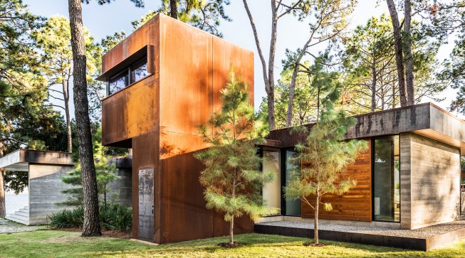 The carbon steel–covered “treehouse” on the north side is linked to the main house by a short glass hallway. 