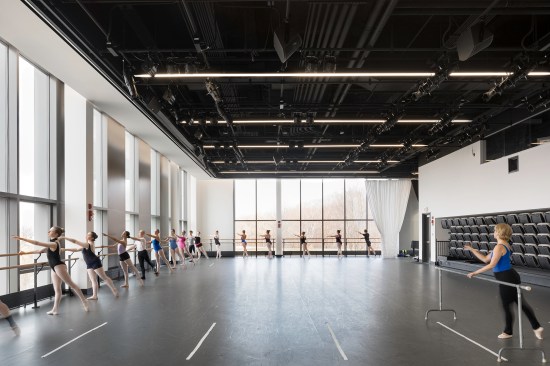 Large windows help showcase the action in a second-floor dance studio to passersby, whether the space is being used for ballet rehearsal or a music performance (it’s outfitted with retractable seating, at right). Though the interior feels different from the sculpture studios downstairs, they synchronize thematically: “You go from a gray concrete floor to a gray sprung dance floor,” Biklen says. “We use color as well as material to connect things.”