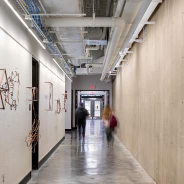 The addition and original building meet along a central corridor. Homosote pin-up panels (at left) front the new studios, and existing openings in Pei’s exposed concrete façade (at right) were repurposed as passways between the two structures. “It provided a lot of continuity, and allowed for a seamless addition,” Biklen says.