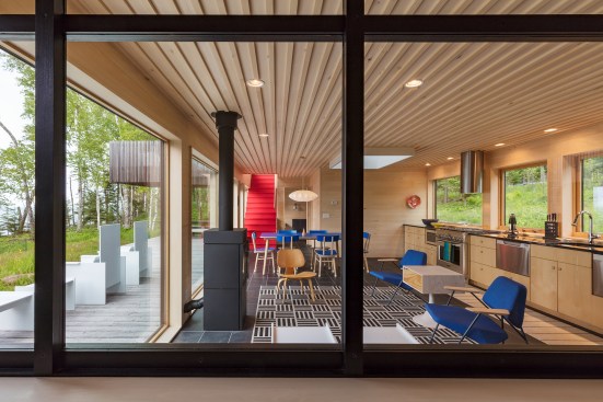The main space on the first floor combines living, dining, and kitchen functions under a Velux skylight, and opens out to a cedar deck via Nordic Doors from H Window Co. 