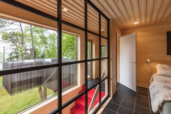 The second-floor master suite has black slate tile floors and an aspen board-and-batten ceiling, and opens onto a cedar-lined balcony.