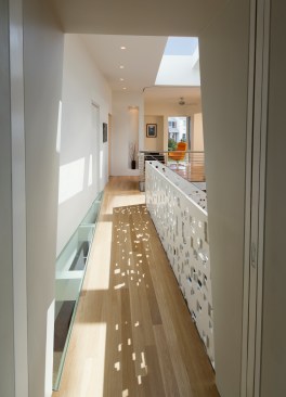 Cutouts in the floor provide a dramatic design element while also letting daylight through to the spaces below. The pattern of light and shadow created by the cutouts in the railing panel mimics the dappled shade of a tree canopy.