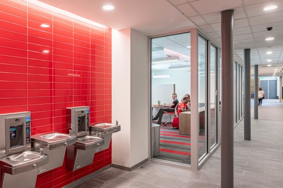 Corridor from The Commons accented with UH Cougar red and views into the community computer lab. Courtesy EYP Architecture & Engineering.