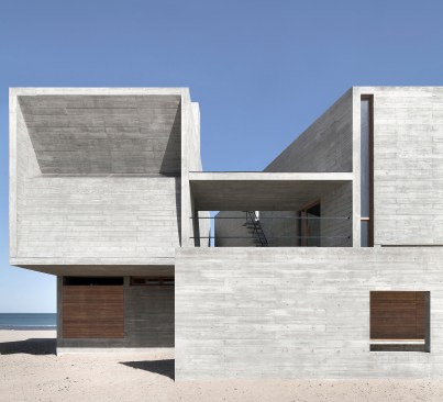 West facade, with freestanding concrete wall in foreground and second-floor terrace behind