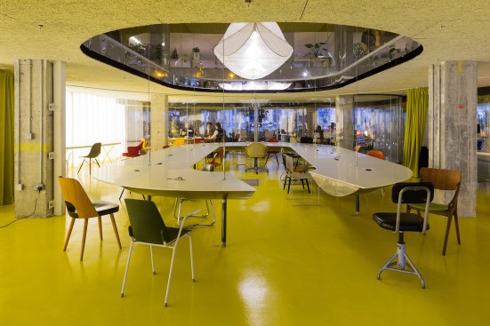 The double-height event space features a custom table that seats 40 for meetings.