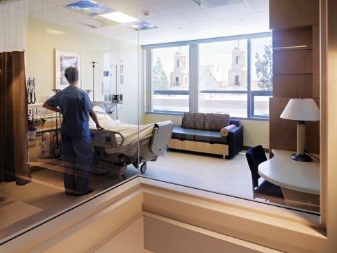 Patient rooms on the upper floors feature operable windows to allow air circulation and natural light as well as luminous artificial skylight panels—backlit glass panels printed with photos of blue skies and flowering tree canopies—above patient beds to provide a respite for bedridden patients. Resilient flooring: Forbo; Marmoleum; forbo.com - Artificial Skylight: Sky Factory; Luminous SkyCeiling in Skies and Blossoms; theskyfactory.com - Ceiling: USG; Lay-in acoustical ceiling tiles; usg.com - Wall Base: Burke; 4" BurkeBase rubber wall base in 209 Gray-Beige; burkeflooring.com