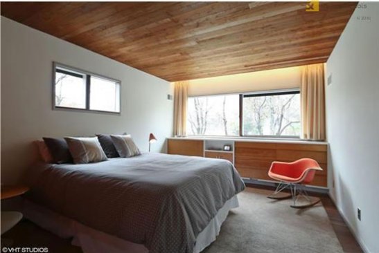 A bedroom in the Snower Residence with Breuer's signature sliding windows and an Eames Rocking Chair (right.)