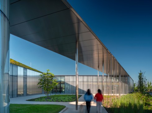 Super-thin steel columns help support a stainless steel canopy at the eastern edge of the building; a courtyard provides green space in front of the main entry (at center). 