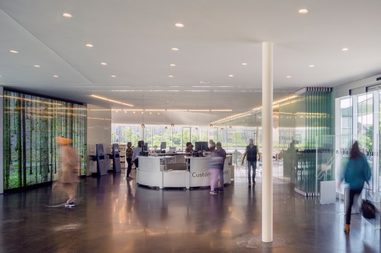 The lobby features polished concrete floors and a customer service desk where patrons can speak to a librarian. A retractable glass partition can divide the space. 