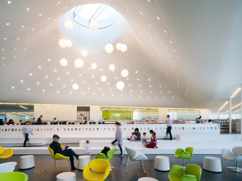 Textured drywall lines the ceiling and the walls that slope up to the 13-foot-wide oculus over what the library calls the active reading atrium; the drywall helps to absorb sound reflected up from the polished concrete floor, which continue throughout. 