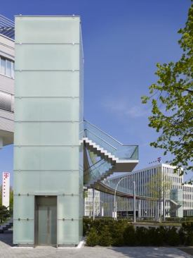 Elevator shafts on each end of the bridge support the slender curved path and connect the buildings of the Deutsche Telekom campus.