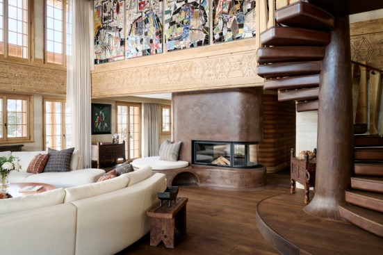 Caption: Interior featuring mural by Rashid Johnson; staircase, fireplace, and wood carvings by Francis Kéré; table by Alexander Lamont; and cushion textiles by Aïssa Dione.