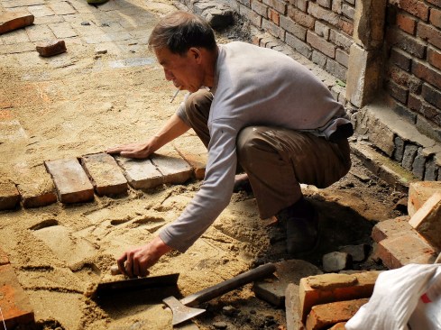 An act of preservation in vain: a resident of a neighborhood slated for demolition makes repairs, Tianjin, 2013.