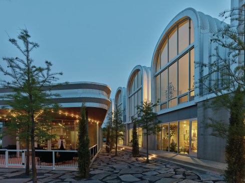 Blackwell designed a row of eight three-story high units, each a separate Quonset hut, aligned along the back of the lot parallel to the street. In front, he placed a restaurant and a small retail container, split by a walkway.