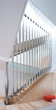The design for the staircase is centered on folded stainless steel. Hung from a structural steel support on the top level of the townhouse, vertical folded pieces create a continuous screen that encloses the two above-grade flights of stairs. Tabs on the bent risers are fitted into slots on the vertical pieces, which created an easy setup for on-site construction and spot-welding.