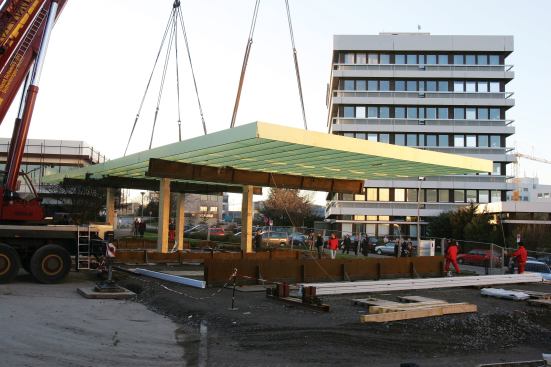 The roof arrived on site in prefab strips, which were bolted together. Then the whole thing was hoisted onto the column pins. When the crane belts were removed, the roof bounced a meter (more than 3 feet) before rocking into place.