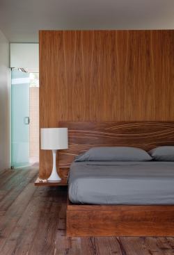 Standing a couple of feet shy of the ceiling, the millwork box presents a flush surface to the bedroom, where it serves as a headboard.