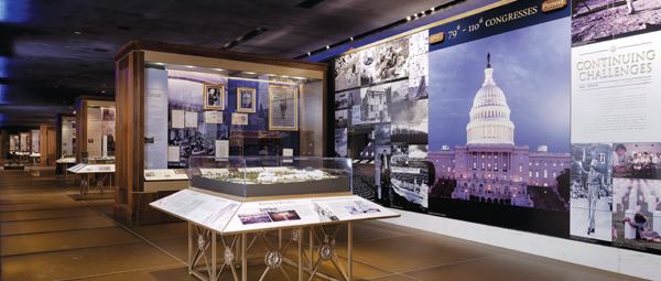 In the entrance lobby, custom fixtures made of solid bronze frames and stone plates are backlit by 42W rectangular compact fluorescent downlights (top). Exhibition Hall primarily uses LED technology to make the display cases the main focus (above).