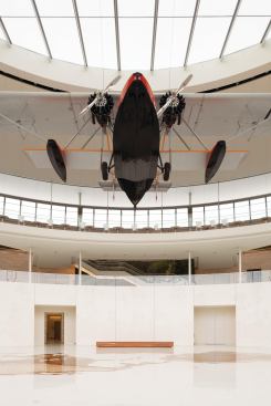 The central skylight brings additional daylight into the space and ensures that the plane is adequately lit during the day. "There was a danger that if there wasn't enough illumination, the plane would go very dark," Robinson says. In a recessed trough around the skylight, focused downlights were placed to illuminate the rest of the triple-height space. Alongside those light fixtures are speakers, with counterparts hidden in the benches on the lower level, that pipe in sounds from Brazil via a link to the National Oceanic and Atmospheric Administration. "It could be the sound of a boat in the harbor," says Kelly Semrau, vice president of global public affairs and communication for SC Johnson, "or it could be voices speaking in Portuguese in a café or noises that you hear in a rainforest. Its very subtle and doesn't play all the time. But when it does, it feels like you're living in that sound." Also calling to mind the Brazilian landscape are the 17 white precast concrete panels that line the lower level. The acid-etched pattern on the 19-foot-high, 11-ton panels forms an image of a Brazilian palm grove, sourced from a photograph taken on H.F. Johnson Jr.'s original 1935 expedition to Fortaleza, Brazil, the city from which the building takes its name.