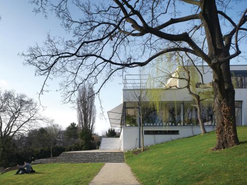 The house steps down the hillside, revealing three living levels as well as a shaded porch on the garden façade.