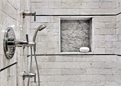The large, elegant shower features a pebbled floor, bench seating, and a wall cutout for shower necessities.

