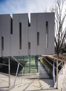 The lower level of the two-story museum is sunk halfway below grade. A glass-enclosed information center (which can also host lectures and some exhibitions) is surrounded by a terrace accessed by stairs.