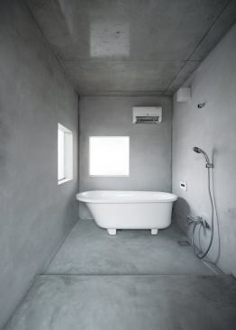 The concrete-lined bathroom is situated just behind the kitchen on the second floor—polycarbonate windows harvest diffuse light from the house’s interior to bring into the minimal space. 