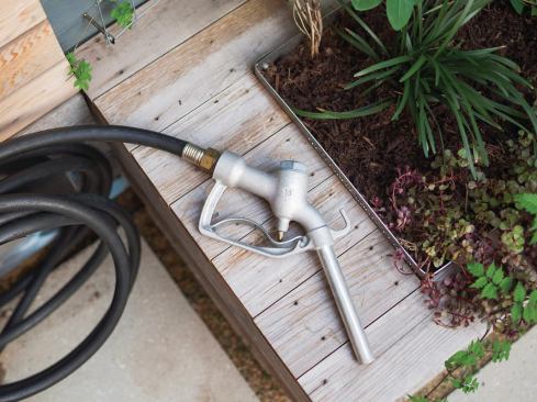 A vintage nozzle salvaged from a gas station sprays water from a 75-gallon rainwater catchment tank, also by Shift_Design.