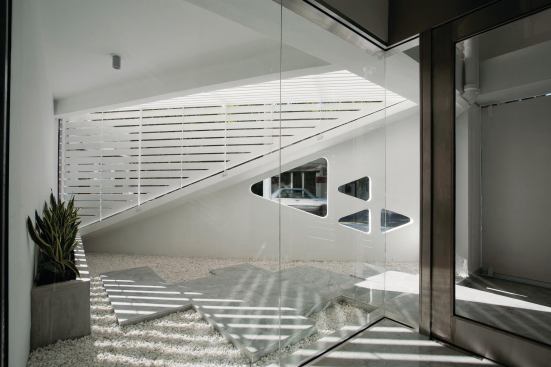 Triangular cutouts in the concrete structure are visible from within the marble-floored lobby.