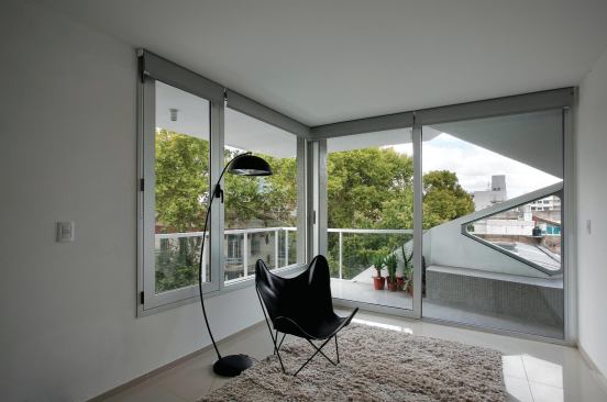 Each of the 13 units includes a balcony, with more of the cutouts visible through sliding glass doors from CNP Sistemas de Aluminio.