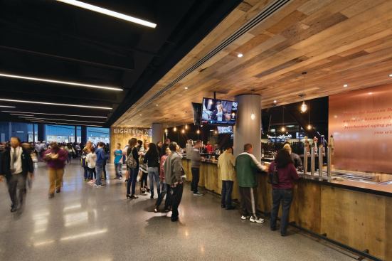  Along the concourse, public areas are marked by a rhythmic progression of strip lights across the ceiling plane. Concessions are wrapped in warm wood to counter the overall black and gray interior. 