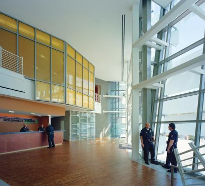 The lobby serves multiple functions: reception, waiting area, and home to impromptu gatherings of officers and neighborhood residents. The glass-enclosed space gains additional security from the canted curtain wall, which is made up of large panes of bulletproof glass.