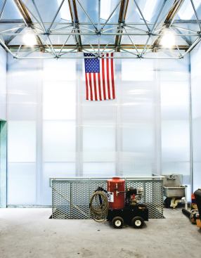 The main interior space is an 800-square-foot ground level garage and workroom. Daylight filters in through the skylights and the white polycarbonate walls, reducing the need for interior lighting. A staircase leads down to the 400-square-foot basement level that houses the heat pumps and other mechanical systems.