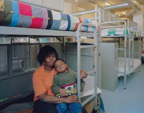 A mother and child sit on a bunk in the women and children's shelter, which is open to both program residents and overnight guests. Many families are coming to stay at the mission, because though men and women sleep in different dorms, a whole family can eat together at mealtimes and interact in public spaces, whereas many shelters have completely different facilities for the two sexes.