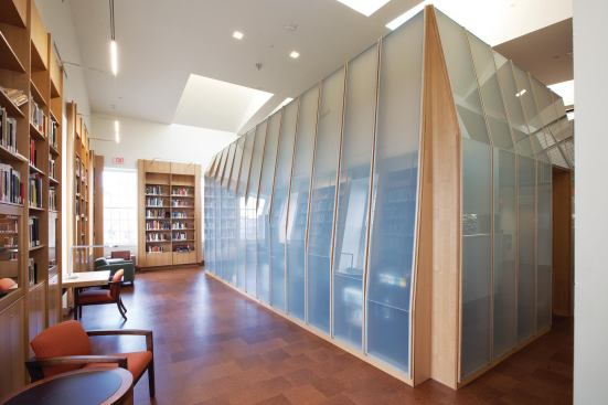 On the double-height second floor, the design team created an office enclosure out of plywood and translucent glass. This allows the surrounding library space to serve as a lively research and social area without creating distractions for those at work. The architects achieved the pleated form of the enclosure by creating a variety of cutting patterns for the wooden fins, and by allowing for coordinating seams in the glass. Two pieces of glass were used in each vertical panel to accommodate the bend.