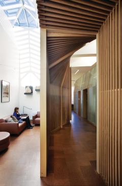 The screen is a recurring theme throughout the interior, warping to create small rooms without cutting off visual access and serving as spot sunshading underneath the existing skylights over workstations.