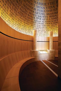 The Room of Remembrance is a double-height volume located on the third floor of the museum. Flanked by Jerusalem stone columns, a book containing the names of those killed during the Holocaust and memories penned by family and community members serves as the focal point of the space. Bent-wood, uplit panels were painted with names of the dead, in English, Yiddish, and Hebrew. First names were used so as to represent as many individuals as possible; the names are 2 1/2 inches high at the base and increase in size as they move toward the ceiling. The names begin in a full, rich black at the base, which turns into a mid-tone black at the top. This was a nod to an idea by a community member to have smoke coming from behind the book of names, a proposal that was not carried out because of fire regulations.