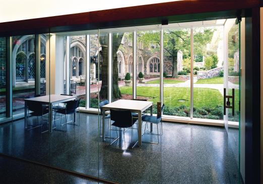 Group study spaces, like this one adjacent to the building entrance, are located throughout Marriott Hall. Floor-to-ceiling windows allow students to view the original 1909 school building. Cues such as the terrazzo floor that matches the hallway (unlike the carpeted classrooms) mark the space as a public area.