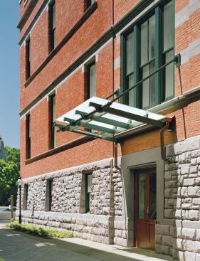A new entrance (opposite), denoted by a glass canopy, is positioned along the façade of the addition, providing an entry close to the heart of campus. When students enter, they can see the old Hunt façades preserved within. Original windows have been converted to display cases for the anthropology department (above left). Steel structural members indicate the perimeter of the self-supporting addition and leave the original façades exposed in lounge areas (above right).
