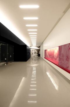 Linear T6 fluorescent lamps are placed uniformly across the lobby corridor ceiling.