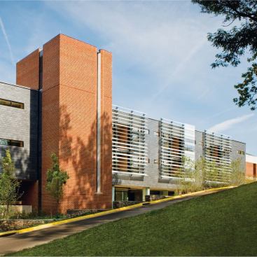 SOUTH ADDITION, 2008

Designed by associate dean William Sherman in collaboration with SMBW Architects, the South Addition adds 26 new faculty offices to the building—a boon in a school whose faculty has tripled since the building’s completion. The addition’s adjacency to the design studios on the third and fourth floors (the faculty had previously been segregated on the lower levels) greatly improves communication with students. “It’s a way to reorganize the way the institution works, as well as the interaction between faculty and students,” Sherman says.

The south façade reflects Sherman’s interest in buildings that respond to climate. The exterior wall incorporates a louver system that combines frosted and clear glass panels that open and close in response to the sun’s movement. Open during the day, they admit light directly into the building; closed at night, they trap the accumulated day’s warmth, creating a greenhouse effect on the porches that connect faculty offices. 

Faculty Architect: William Sherman 

Architect of Record: SMBW Architects 

Structural: Fox & Associates

Civil Engineer: Draper Aden Associates 

M/E/P: Hurd & Obenchain 

Contractor: Donley’s Construction 