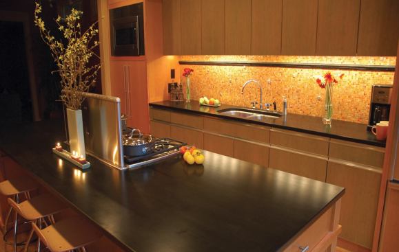 As a backup to the sink, iridescent mosaic glass tiles are a sparkling counterpoint to the abundance of warm wood.