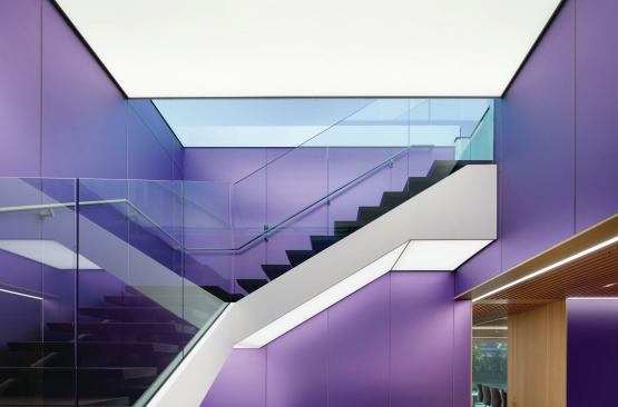 A backlit stretched ceiling-- controlled by a daylight-responsive dimming system--and purple-etched laminated glass walls glow without the trace of any fixture silhouette. 